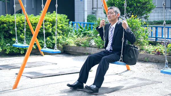 Middle aged businessman with dementia is lost as he rides on swing.